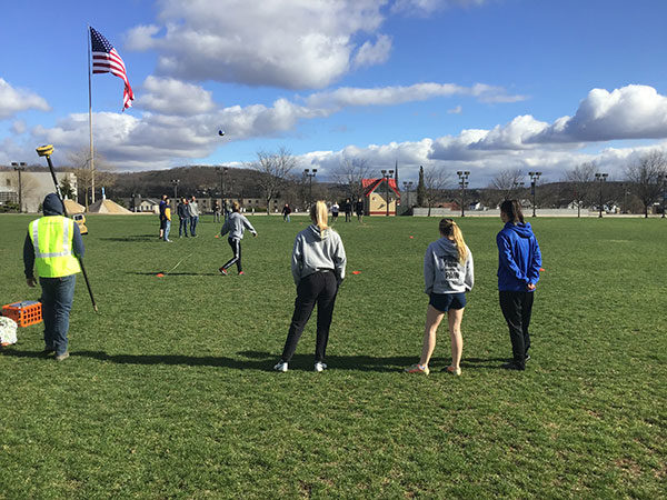 Francesca M. Timpone, of Smithtown, N.Y., sends the soccer ball on its trajectory while a surveying technology student, student-athletes and a coach collectively observe. 