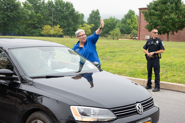 Traffic control straight from the top: With a wave and a smile to a volunteer up the line, the president greenlights the next vehicle for unloading (with backup from Penn College Police Officer Adam J. Haffley).