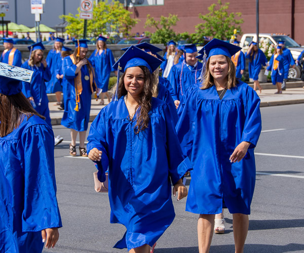 Degree candidates cross West Fourth Street on their way to the future.