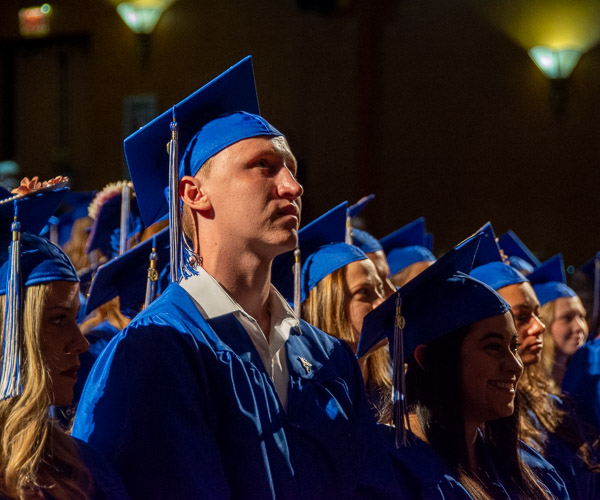 Students rise to turn their tassels.