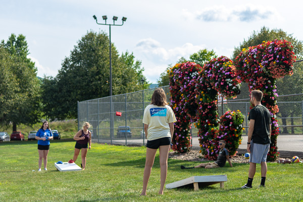 Students enjoy outdoor games against a floral backdrop.
