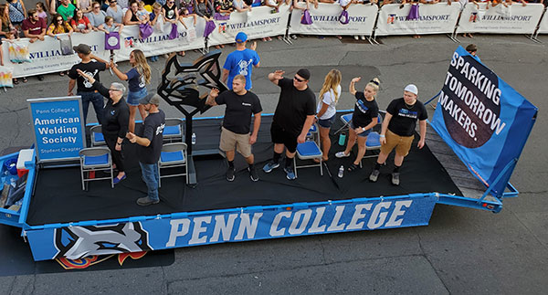 The college float passes beneath the overhead lens of Elliott Strickland, chief student affairs officer.