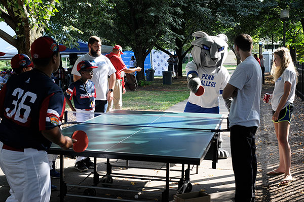 The college mascot, accompanied (at right) by students Josh Rosenberger, of Waynesboro, and Bria O. Schneider, of York, meets a Mid-Atlantic player – representing Elizabeth, N.J. – over the pingpong table.