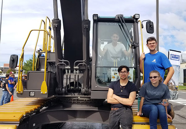 Students pose in and around the excavator.