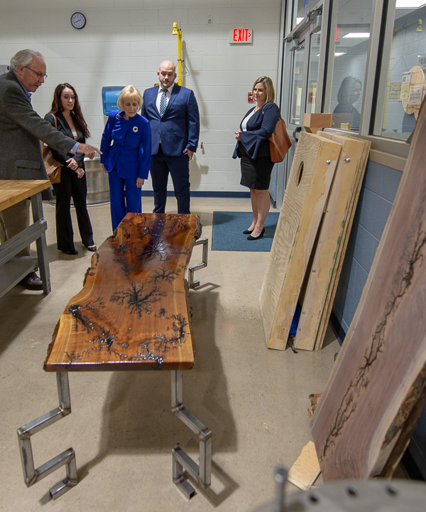 In the college's makerspace, Tom Gregory, associate vice president for instruction, points out a student’s handcrafted live-edge walnut wood table, featuring artistic touches achieved with wires and electric arcs. The table is the handiwork of Michael C. Aja, of Novi, Mich., enrolled in welding and fabrication engineering technology.