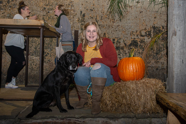 A 7-year-old black lab named Ivan enjoys the Saturday evening festivities at New Trail with his “mom,” Christa L. Watson, ’18, business administration: management concentration, who is director of development at the Lycoming County SPCA. In the background are Watson’s friends Danielle M. Logan, ’18, dental hygiene, and Sarah I. Tielmann, ’18, baking and pastry arts. <br />
<br />
