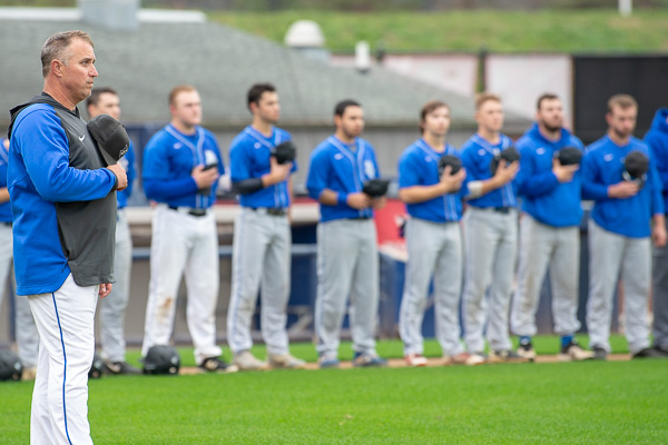 Assistant Baseball Coach Levon A. Whitmyer and players honor the playing of the national anthem. A building construction technology instructor, Whitmyer is also an alumnus and a member of the first Penn College baseball team. 