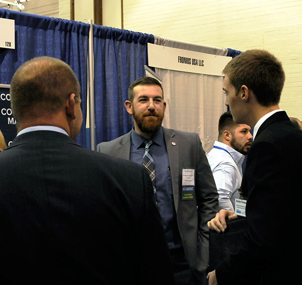 Skylar L. Gingrich, a 2013 grad in residential construction technology and management: building construction technology concentration, talks with visitors to the Benchmark Construction Co. booth. A project manager with the Lititz firm, the former Wildcat baseball player was a 2018 inductee to the Penn College Athletics Hall of Fame.
