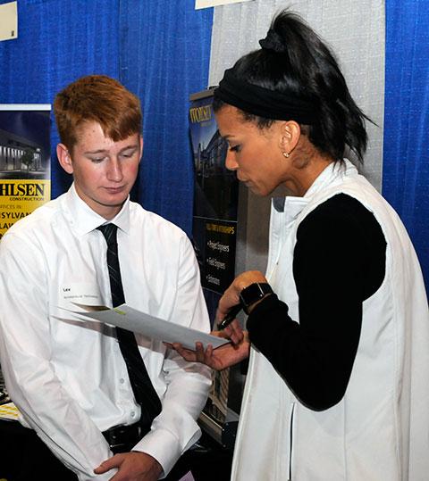 Lex R. Yocum, of Watsontown, enrolled in building science and sustainable design: architectural technology concentration, assesses his options at the Larson Design Group display. Assisting in his exploration is Kaylee Caruso, a recruiter for a firm where Penn College grads represent a quarter of the workforce.