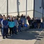 Students gather around a sign commemorating High Steel's fabrication of approach spans for replacement of the former Tappan Zee Bridge over New York's Hudson River.
