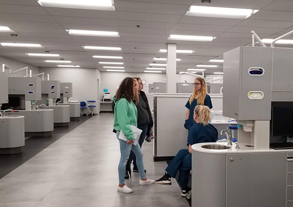 Second-year majors Emily K. Conklin (standing) and Jordyn M. Kahler talk with guests in the expansive, state-of-the-art Dental Hygiene Clinic.
