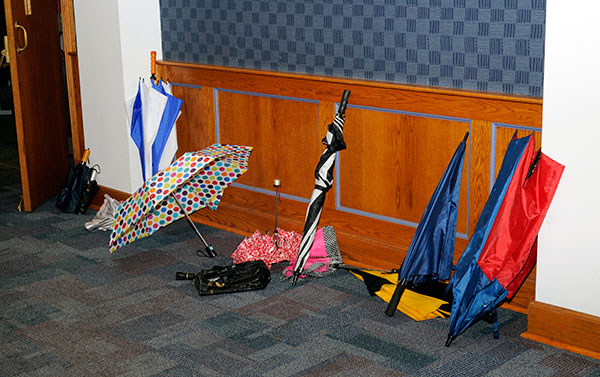 Umbrellas drip-dry in a temporary storage area outside the auditorium.