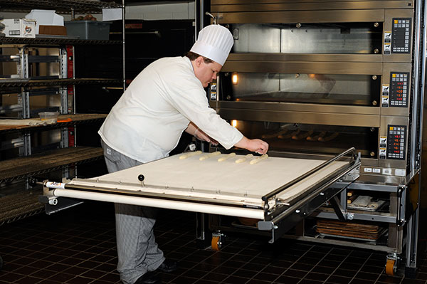 Culinary arts and systems student Aaron Timmons, of Greencastle, preps baguettes for the oven during a kitchen demonstration.