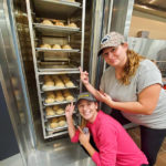 Stevie A. Petrison, of Landenberg, and Victoria A. Sosar, of Berwick, celebrate their handiwork as it heats in the baking lab’s new, industry-standard Revent ONE26 Rotating Rack Oven. Both students are in business administration: sport and event management concentration.
