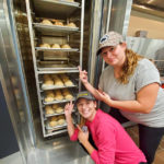 Stevie A. Petrison, of Landenberg, and Victoria A. Sosar, of Berwick, celebrate their handiwork as it heats in the baking lab’s new, industry-standard Revent ONE26 Rotating Rack Oven. Both students are in business administration: sport and event management concentration.