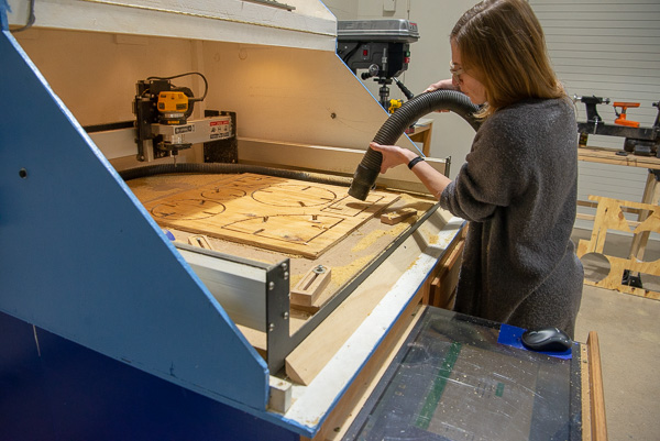 At the CNC router, Andrea McDonough, a Williamsport Area High School art educator, removes sawdust from her work-in-progress.
