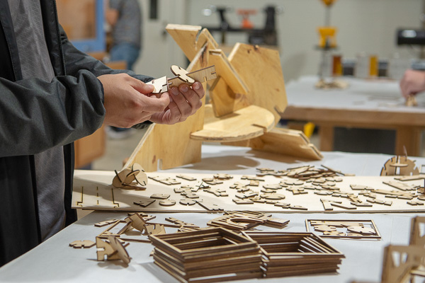 Like puzzle pieces, small wood cutouts are combined to create larger sculptures (like the one in the background).