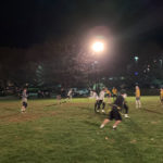 The blur of a crisp night game depicts the busy back-and-forth action.