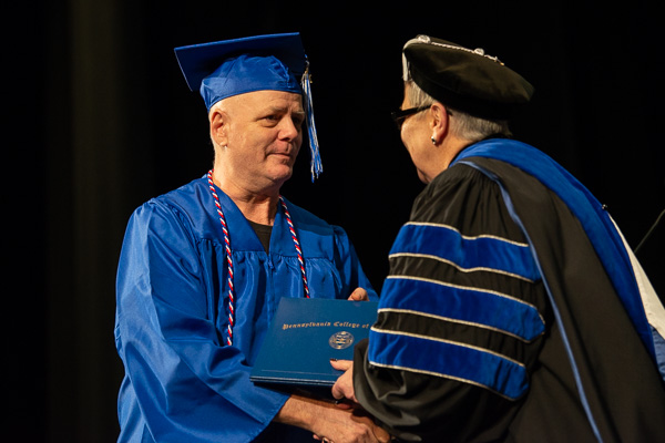 Graduating veteran James A. Dansereau – earning degrees in electromechanical maintenance technology and electrical technology – accepts Gilmour's sincere gratitude and best wishes.