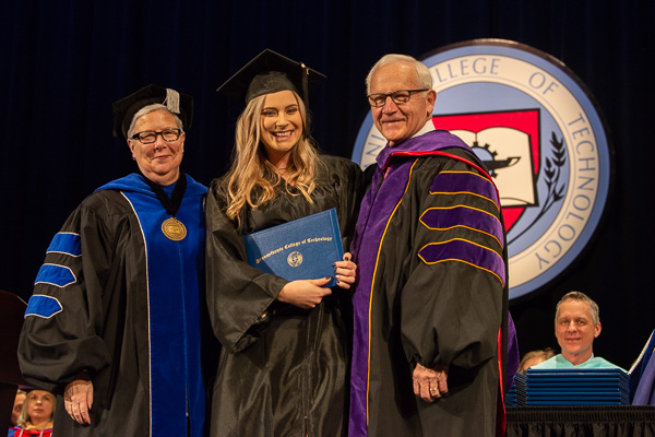 The final graduate to cross the stage: the student speaker, who then enjoyed a photo op with the president and board chairman. (Michael J. Reed, vice president for academic affairs and provost, is seated at right.) 