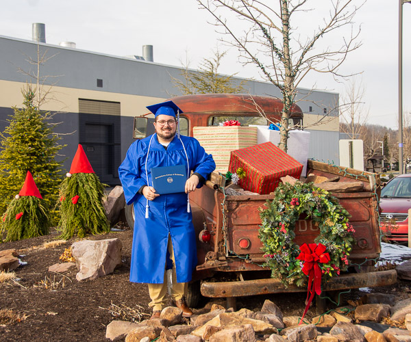 Cody R. Lenhardt, of Drums, heavy construction equipment technology: technician emphasis, poses with the truck that, in the summer, serves as a water feature, but was made equally attractive for the holidays by the college’s horticulturalists.