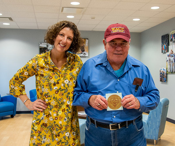 Accompanied by Kimberly R. Cassel, director of alumni relations, Lee I. Miller, ’67, shows off the WACC parking pass he paid a few cents for in the mid-1960s, along with his class ring.