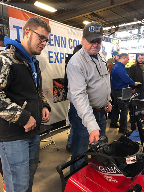Instructor Timothy S. Turnbach coaxes a visitor to try the arc-welding trainer from Lincoln Electric.