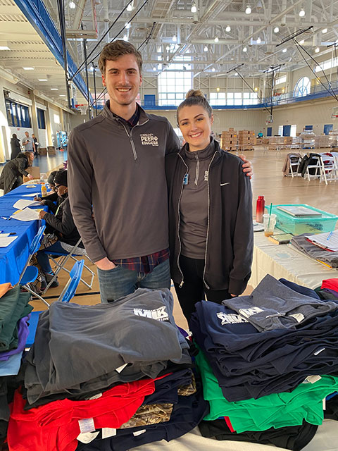 Community peer educators Ethan M. McKenzie and Breanna M. Snyder staff the T-shirt table.