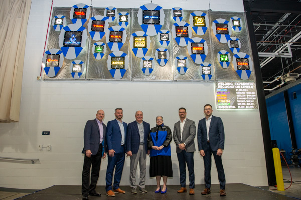 President Gilmour (still wearing her ribbon-cutting welding jacket) poses with representatives of Miller Electric Co., the Titanium Level supporter which was the first to partner with the college on the project.