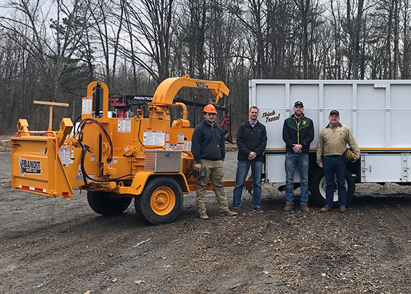 Michael S. Shreiner, a 2019 forest technology graduate, joins Pennsylvania College of Technology forestry personnel alongside the hand-fed chipper that he delivered to the college in late January. From left are Nathan D. Avery, laboratory assistant for forest technology; forestry instructor Eric C. Easton; Shreiner; and Andrew Bartholomay, assistant professor of forestry.