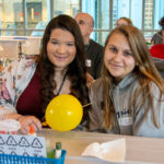 Taking advantage of their chemical knowledge, students stick a skewer through a balloon – with the help of lotion to make the skewer slip between the molecules in the latex without popping the balloon.