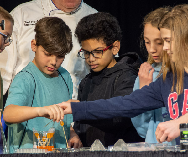 During a “Taste of Technology” presentation by Chef Frank M. Suchwala, associate professor of hospitality management/culinary arts, children drop orange soda into a solution that includes alginate (a product of seaweed) to create tasty, caviar-sized spheres.