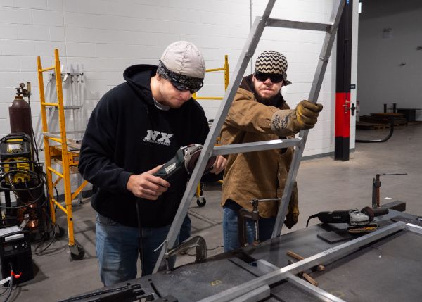 Welding students Nolan Durecki (left) and Christian A. Novick assist with grinding edges of the A Wall. 