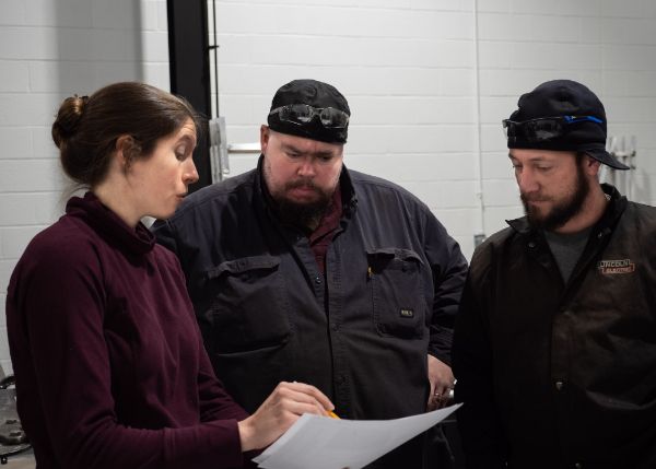 Gillean Denny, chief architectural designer for the Living Chapel, reviews some design changes with Holland and Colton. As a Penn State student in 2002, Denny visited the Penn College masonry lab with her classmates for a day of hands-on experience.
