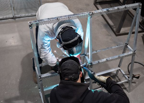 Colton and welding instructor Cody W. Wolfe apply one of thousands of welds on the structure. 