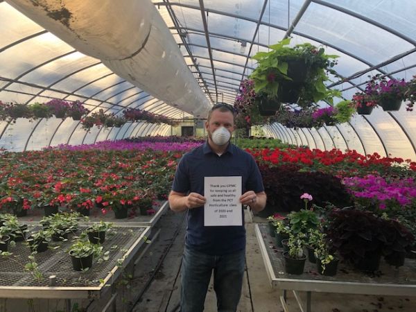 Faculty member Justin Shelinski holds a sign on behalf of horticulture students, thanking UPMC 