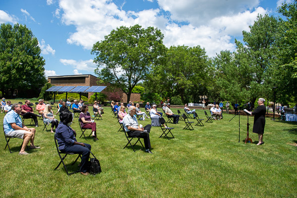 The president honors retirees, joined on the campus lawn by family members and co-workers.