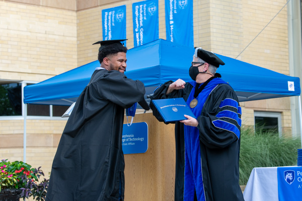 President Gilmour sanitized after every diploma handoff, leaving it up to everyone how they wished to be acknowledged. Malachi J. Atkinson, a web and interactive media graduate, chose an elbow bump.
