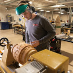 Mason Peters, applied management and heating, ventilation & air conditioning technology, shapes a piece from cherry and black walnut that was harvested at the college's Schneebeli Earth Science Center.