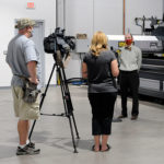 Webb is interviewed in front of the CNC plasma cutter, among the new equipment in the college's expanded labs.