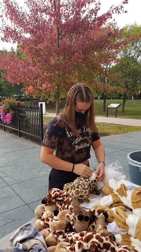 Serena V. Bergeron, an automotive technology management: collision repair concentration student from Lansdale, stuffs a plush leopard takeaway near a canopy of fall foliage.