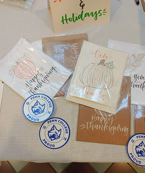 Stationery by local artist Sara Kiehl, including Penn College decals, awaits completion and mailing to students' families.
