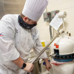 Patrick E. Hufnagle, of Antes Fort, places the dough for a batch of pumpkin cranberry rolls in a dough divider/rounder.