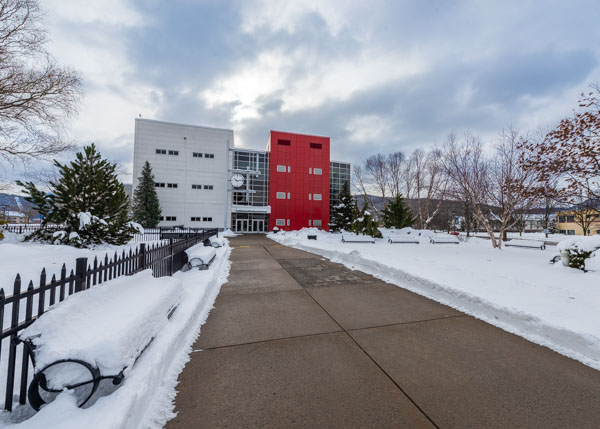 Madigan Library cuts an imposing figure beneath lingering snow clouds, a well-cleared path beckoning students and employees alike.
