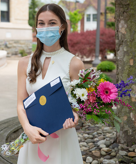 Students – including Regan E. Miller, a nursing major from Wyalusing, proudly sporting flowers, her induction certificate and a membership pin – enjoyed posing outside the ACC for family photos. (Inductees were asked by chapter officer Jacob A. Bamonte to wear their pins on campus for the next week, "not for self-glorification, but to aid in making the aims and ideals of Alpha Chi better known in this center of education.")