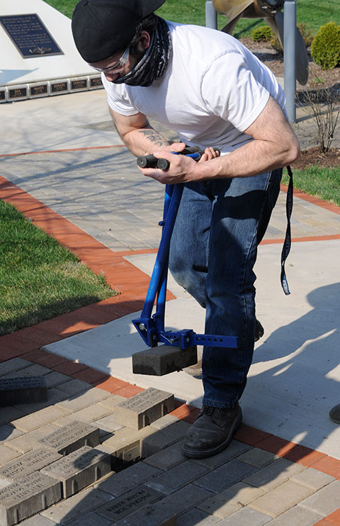 Collazo wields an extraction tool to easily pull a blank paver, making room for an engraved one.