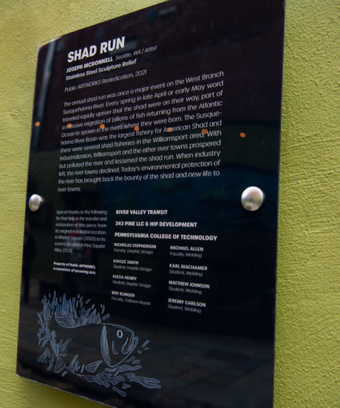 The names of Penn College instructors and students who participated in the "Shad Run" restoration are displayed on a commemorative plaque, which also explains and illustrates the titular event: "Every spring in late April or early May word traveled rapidly upriver that the shad were on their way, part of a massive migration of billions of fish returning from the Atlantic Ocean to spawn in the rivers where they were born. The Susquehanna River Basin was the largest fishery for American Shad and there were several shad fisheries in the Williamsport area. With industrialization, Williamsport and the other river towns prospered but polluted the river and lessened the shad run. When industry left, the river towns declined. Today's environmental protection of the river has brought back the bounty of the shad and new life to river towns."