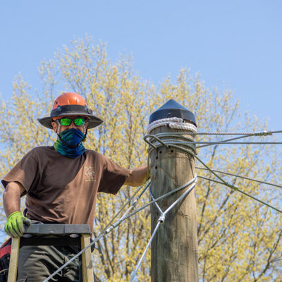 Working on weatherproofing, Draus installs caps on the poles to prevent bees from nesting in them.