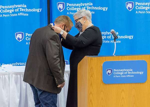 The Veronica M. Muzic Master Teacher medal – carrying the literal weight of institutional importance – is placed around Sones' neck by President Gilmour. He is the 34th person to be awarded the college's highest faculty honor, named for its first recipient.