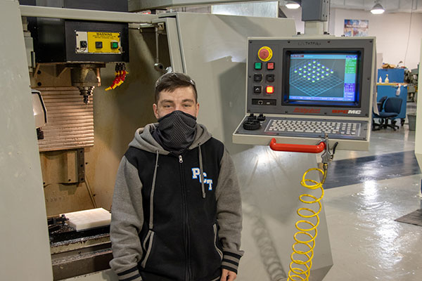McCorkle stands alongside the computer numerical control vertical machining center used to manufacture nylon food molds for the college’s culinary arts program.